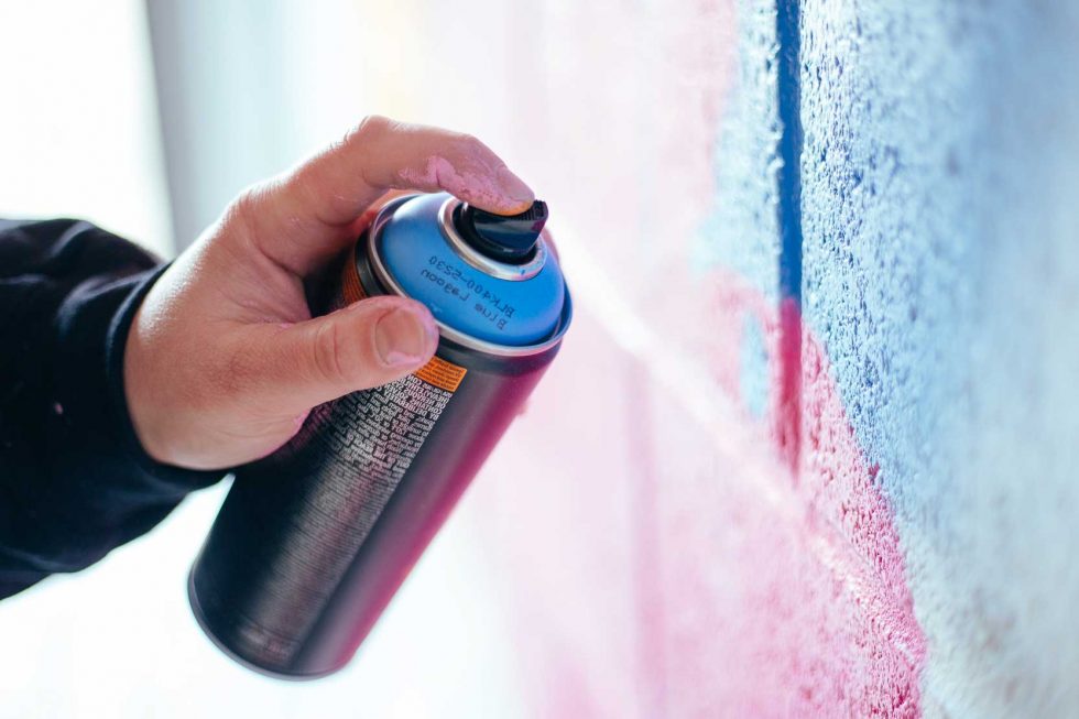 Graffiti-artist-spray-painting-wall
